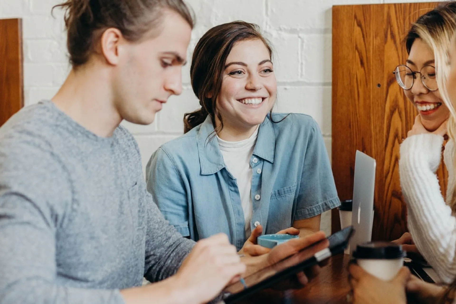 Four people gathered around a tablet at a cafe
