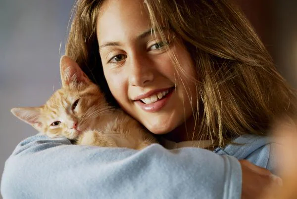 Smiling girl cuddling a ginger cat