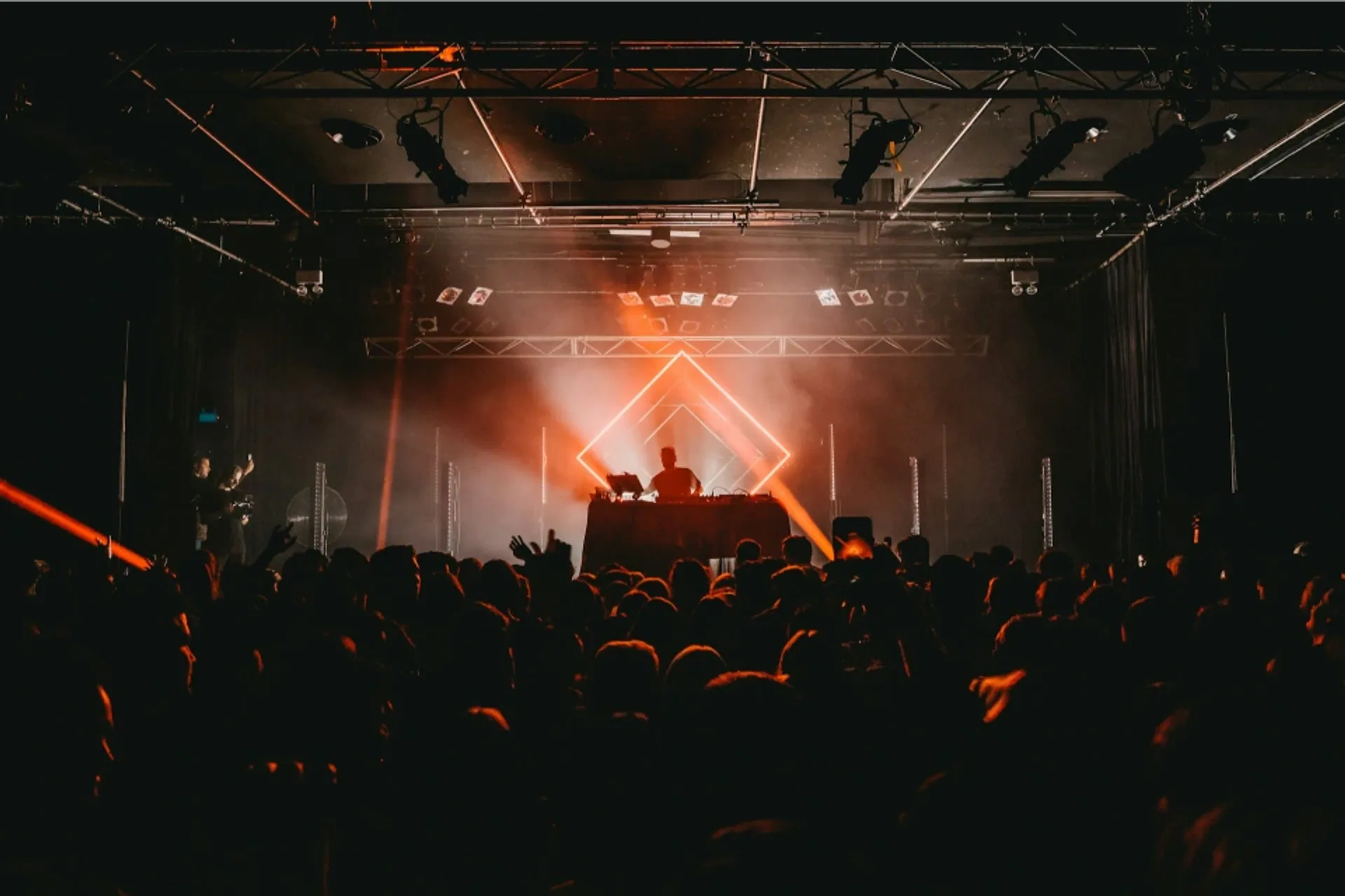 Concert audience watching a DJ perform under stage lights