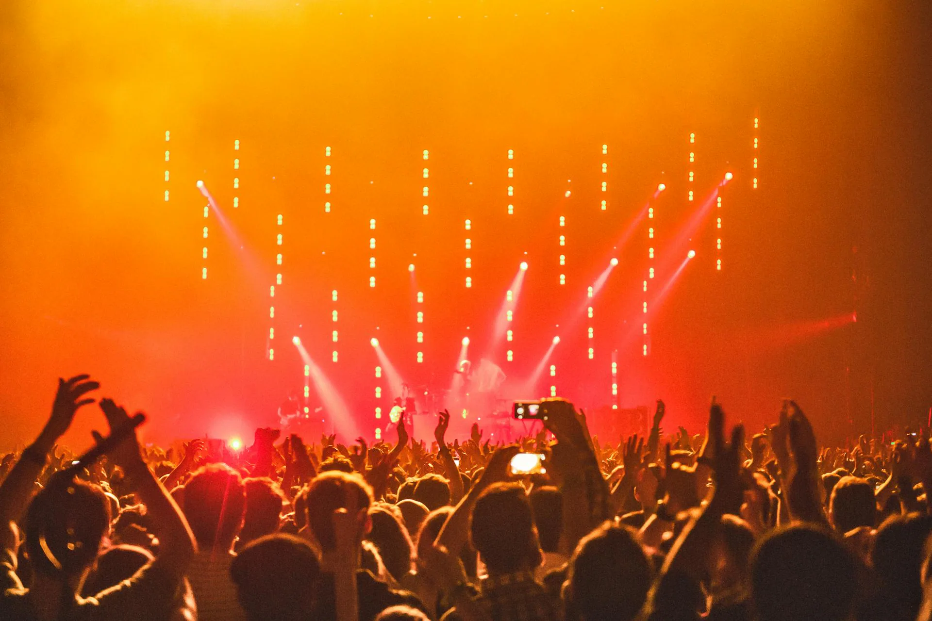 Crowd at a live concert under orange stage lighting
