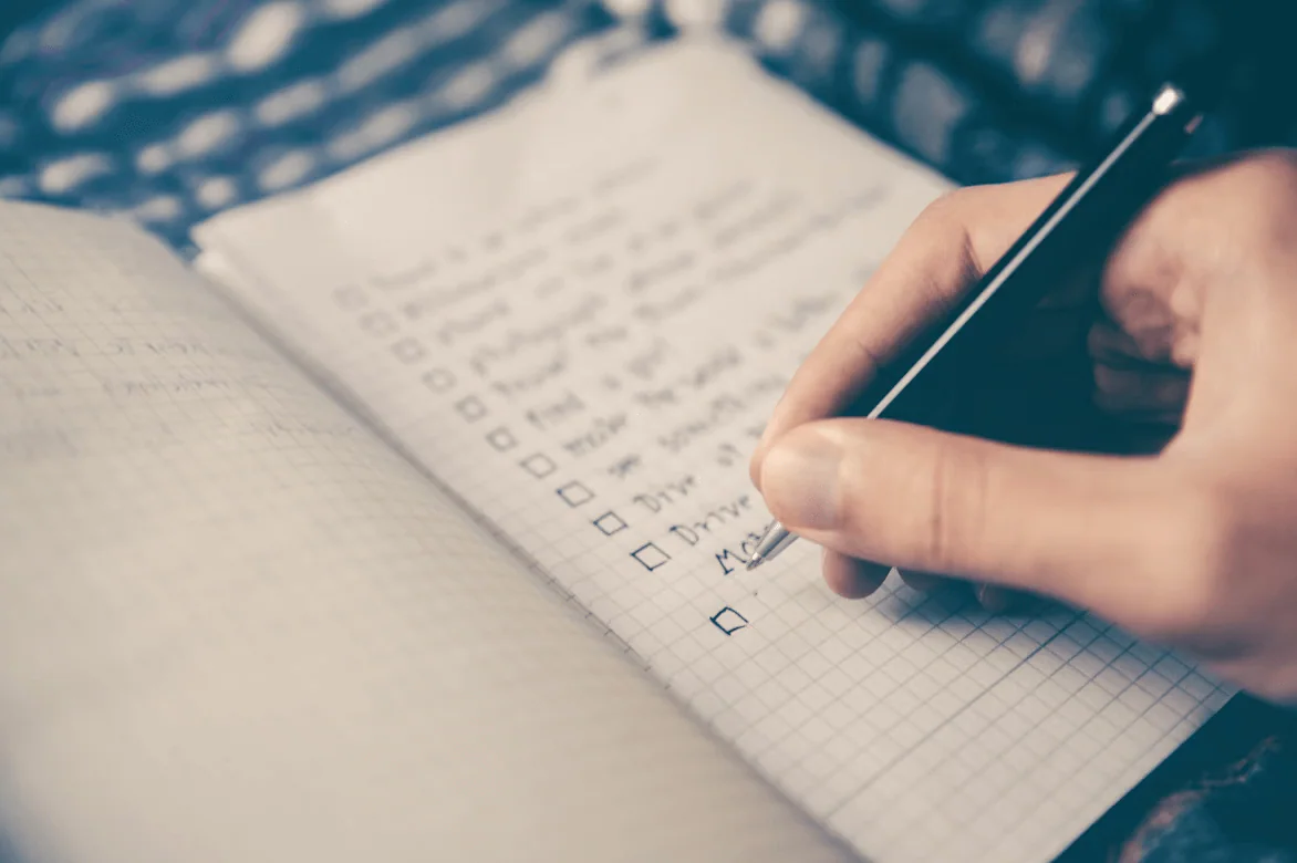 Hand writing tasks on a checklist in a notebook