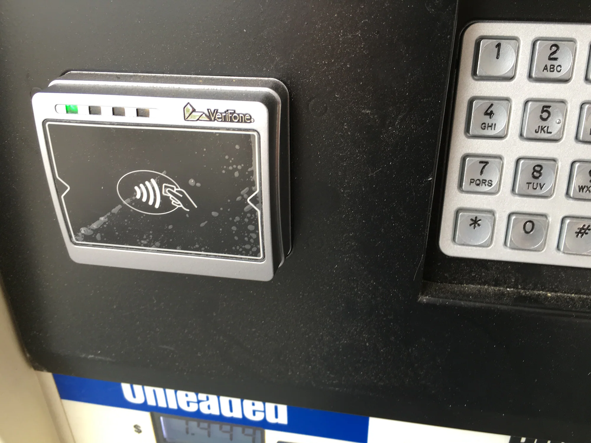 Contactless payment reader installed beside a gas pump keypad