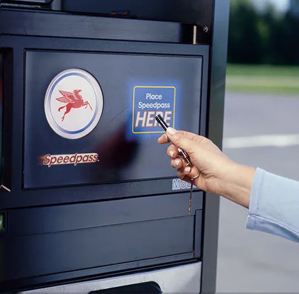 Hand presenting an Exxon Mobil Speedpass key fob to a reader