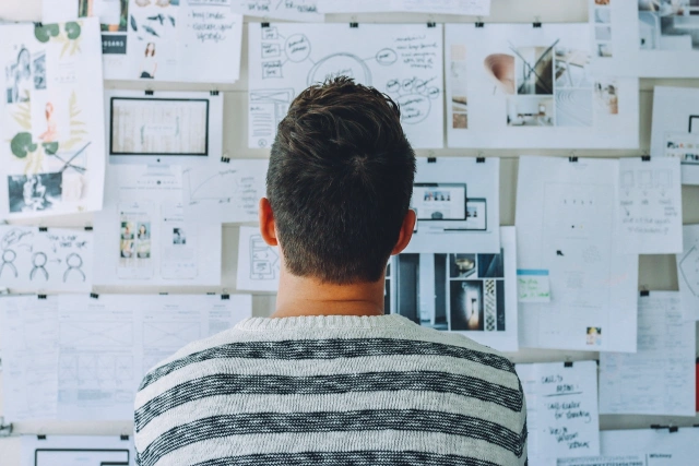 Person reviewing a wall of project plans and design work