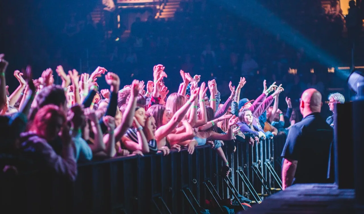 Concert audience with raised hands behind a security barrier