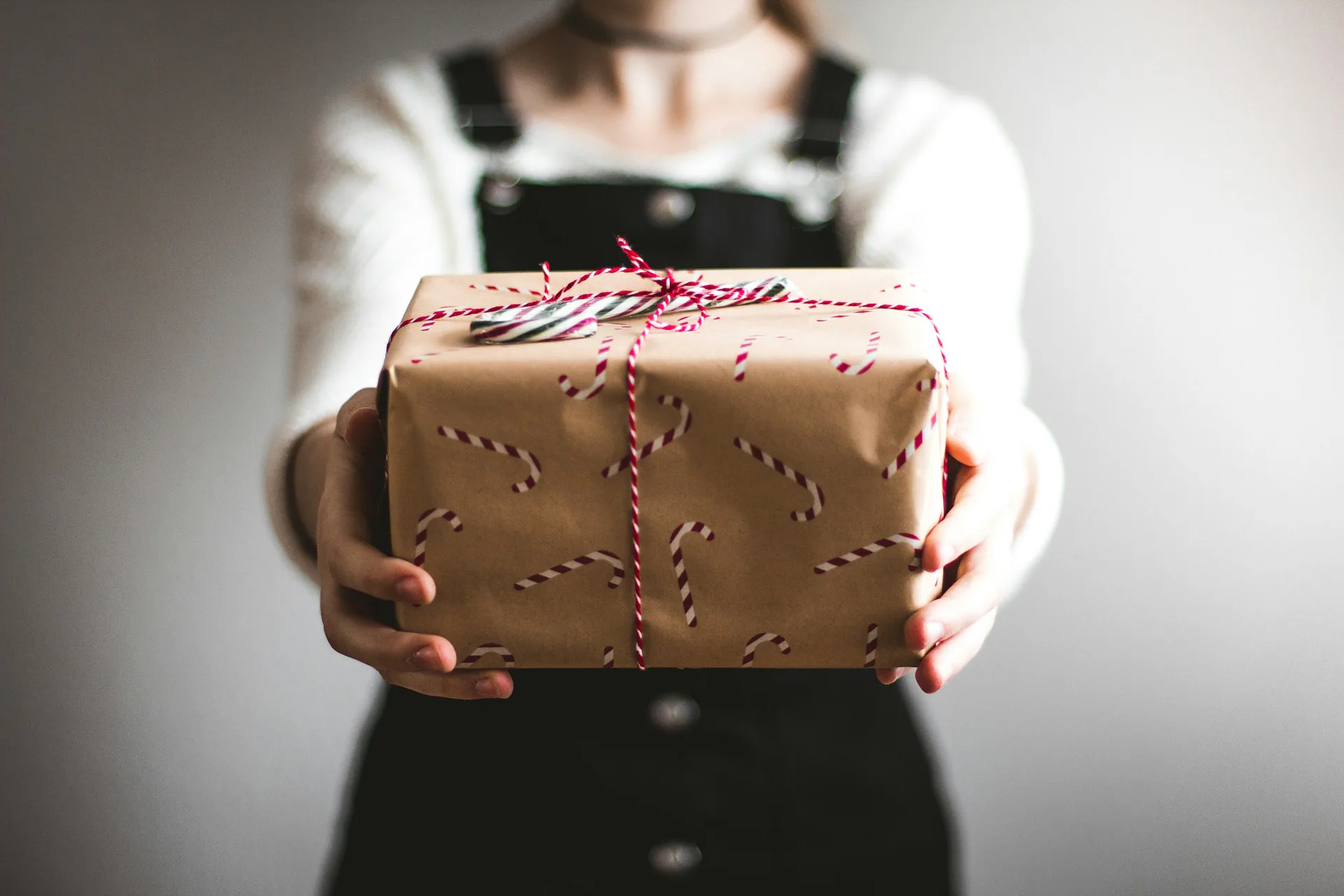 Person holding a wrapped gift decorated with candy canes